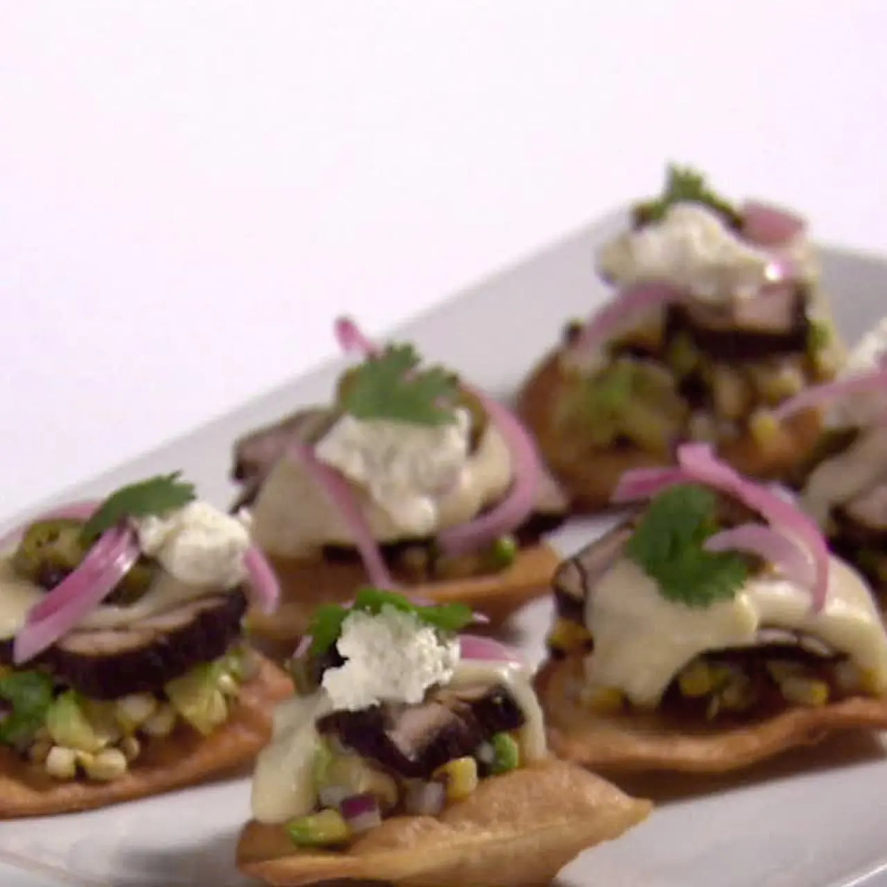 Pork Tenderloin Nachos with Mornay Sauce, Avocado-Corn Relish, Charred Jalapeno and Goat Cheese